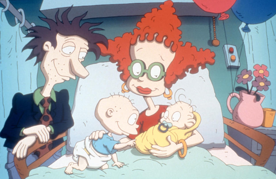 Stu, Didi, and Tommy Pickles meet newborn baby Dil Pickles in a hospital setting, adorned with balloons and flowers in "The Rugrats Movie"