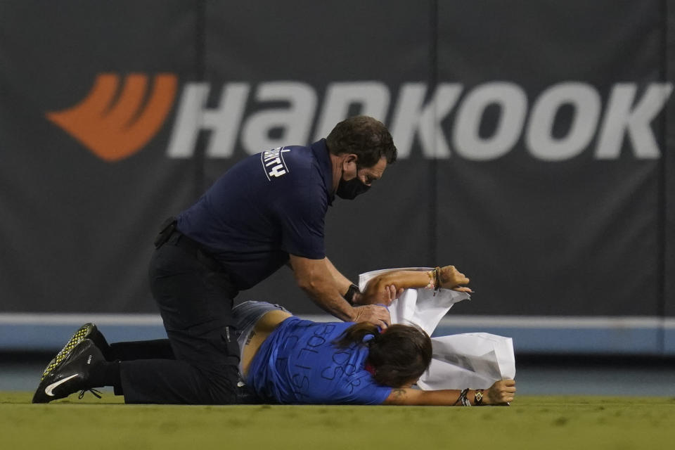 A fan who made her way on to the field is tackled by security personnel during a baseball game between the Arizona Diamondbacks and the Los Angeles Dodgers Wednesday, Sept. 15, 2021, in Los Angeles. (AP Photo/Ashley Landis)