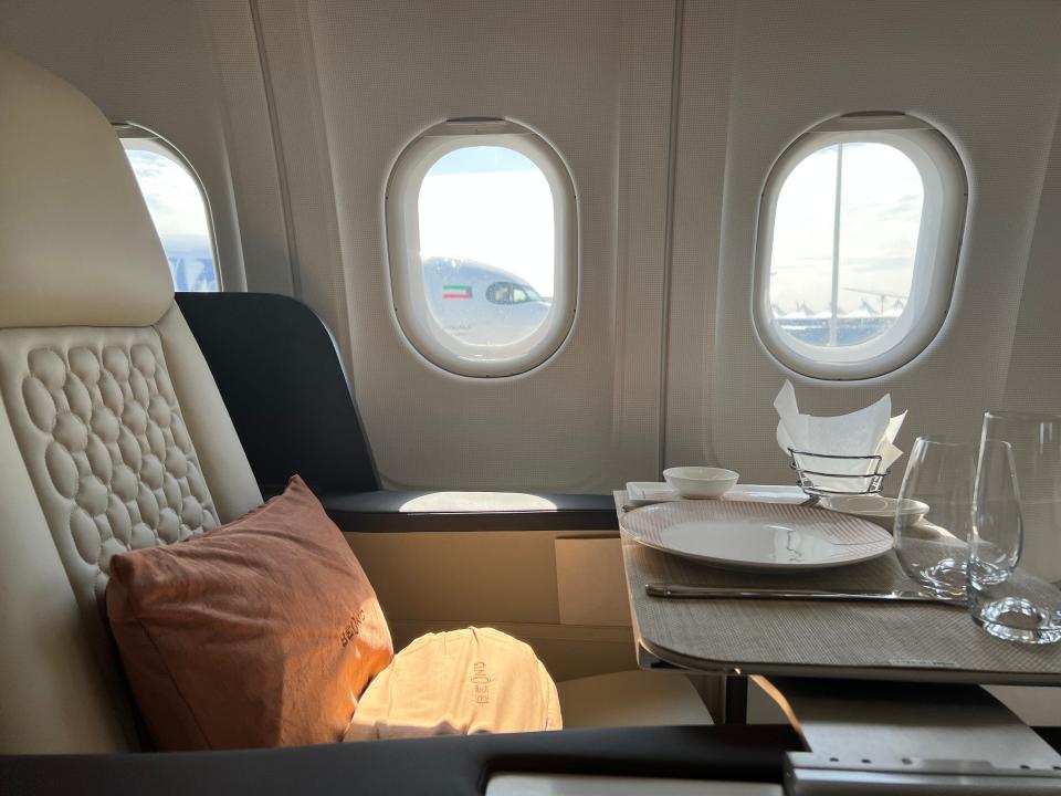 A side view of a seat on Beond A319 shows the windows, and the tray laid out for dinner service with two glasses and a plate