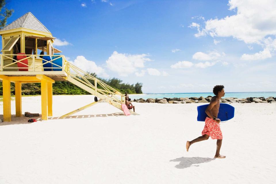 Man running with a body board on a beach in Barbados