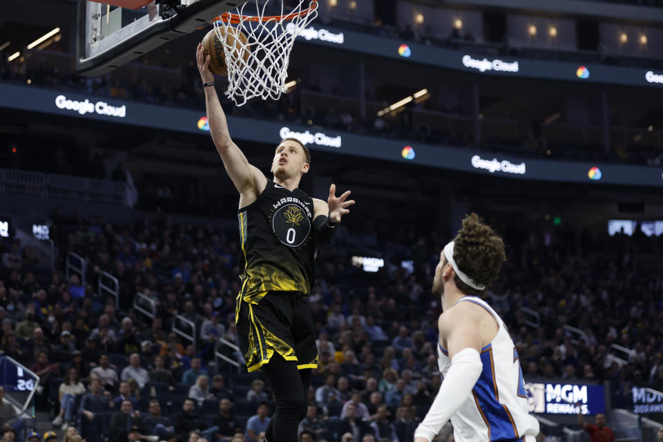 Golden State Warriors guard Donte DiVincenzo (0) shoots against Washington Wizards forward Corey Kispert, right, during the first half of an NBA basketball game in San Francisco, Monday, Feb. 13, 2023. (AP Photo/Jed Jacobsohn)