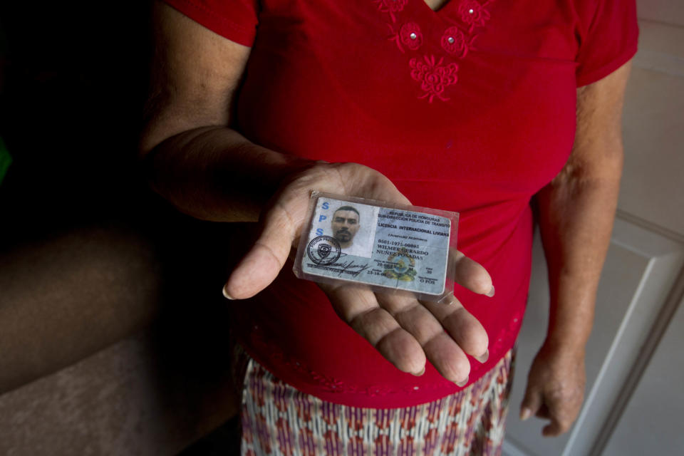 In this Nov. 3, 2018 photo, Haydee Posadas shows the driver's license her son Wilmer Gerardo Nunez was carrying when he was blindfolded and shot dead on his journey north, at her home in Ciudad Planeta neighborhood of San Pedro Sula, Honduras. When an Argentine forensics team found out about Nunez's ID, they tried to track down the family. The Catholic church helped in the search since the team refused to set foot in Ciudad Planeta. (AP Photo/Moises Castillo)