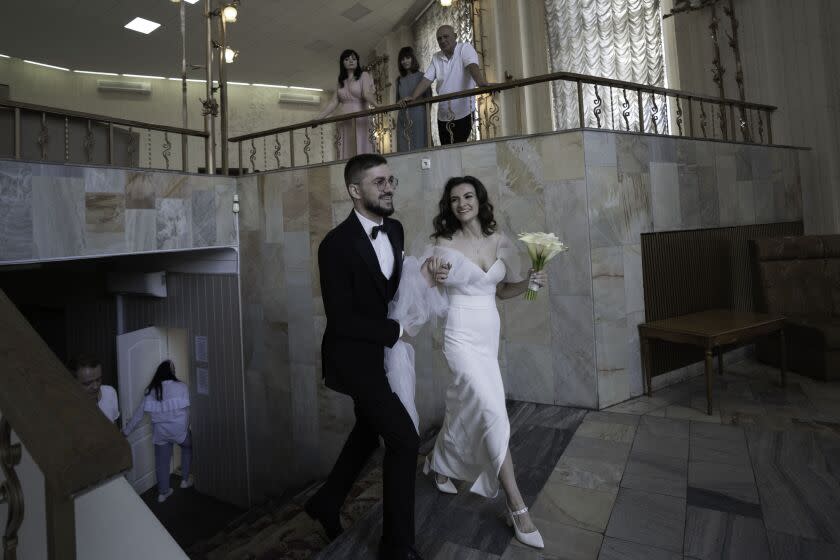 Kyiv, Ukraine -A couple waits walks to the hall before a small gathering during their wedding at Kyiv's central registry office on Saturday, July 23, 2022 in Kyiv, Ukraine. What would have usually been elaborate events have been reduced to brief ceremonies, sometimes in short intervals, before the groom returns to the front to continue their role in Ukraine's war with Russia.(Kyrylo Svietashov / For the Times)