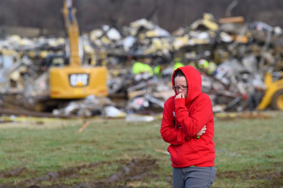 A woman walks away from what is left of the Mayfield Consumer Products Candle Factory as emergency workers comb the rubble after it was destroyed by a tornado in Mayfield, Kentucky, on December 11, 2021. / Credit: JOHN AMIS/AFP via Getty Images