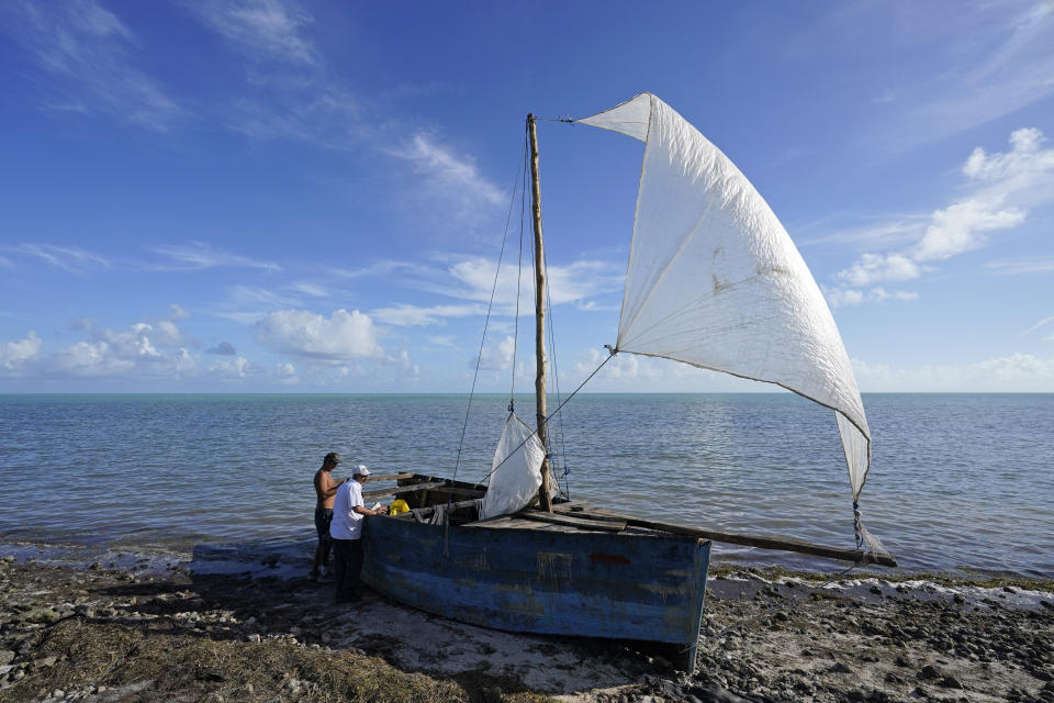 Archivo - Dos transeúntes observan el 4 de enero de 2023 un bote rústico abandonado luego de que en él llegaron decenas de migrantes en Islamorada, Florida. (AP Foto/Wilfredo Lee, Archivo)