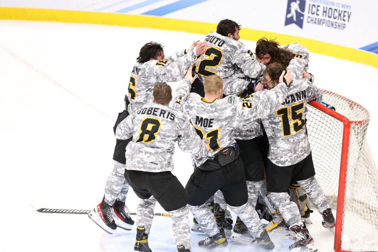 The Adrian College men's hockey team piles up on the goal after beating SUNY Geneseo in the NCAA Division III Men's Ice Hockey National Championship Saturday at Herb Brooks Arena in Lake Placid, New York.