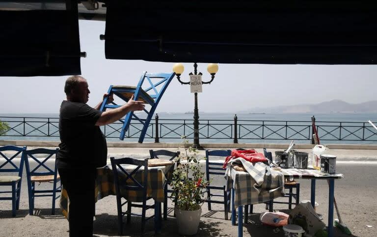 Un hombre abre su restaurante en un pueblo cercano a Atenas, en Grecia
