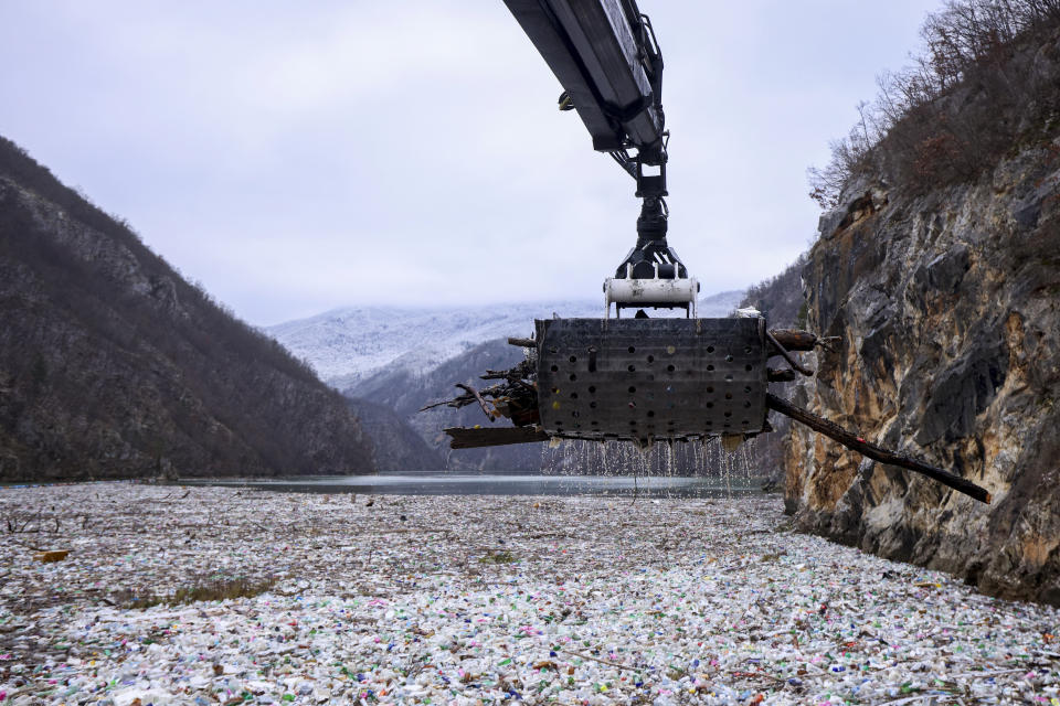A crane moves as it collects waste floating in the Drina river near Visegrad, Bosnia, Wednesday, Jan. 10, 2024. Tons of waste dumped in poorly regulated riverside landfills or directly into the rivers across three Western Balkan countries end up accumulating during high water season in winter and spring, behind a trash barrier in the Drina River in eastern Bosnia. (AP Photo/Armin Durgut)