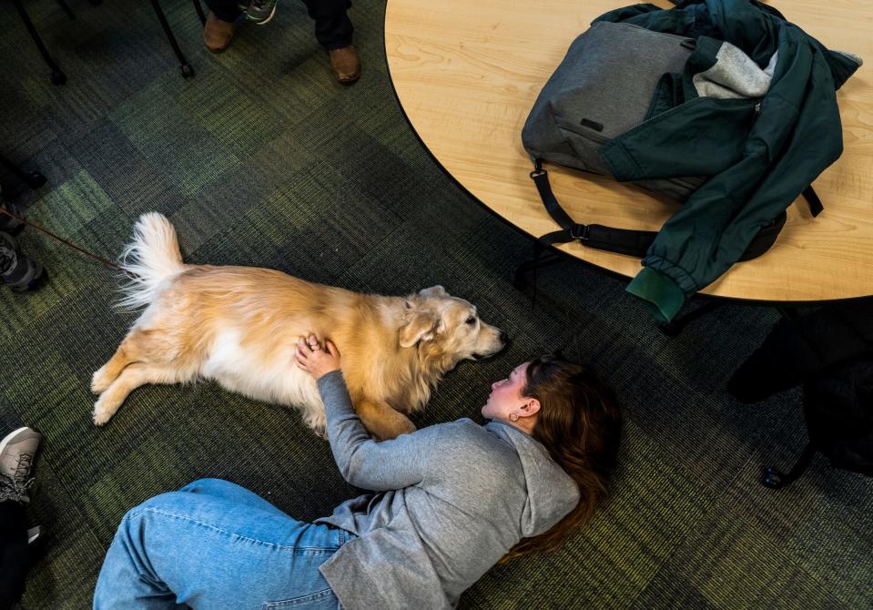 Michigan State University freshman Kaylin Caper lays with Jake, a golden reteiver, while spending time with other students petting therapy dogs in the Main Library on the campus in East Lansing on Friday, Feb. 17, 2023, to help students/faculty in the aftermath of the mass shooting on campus that left three students dead and five in critical condition.