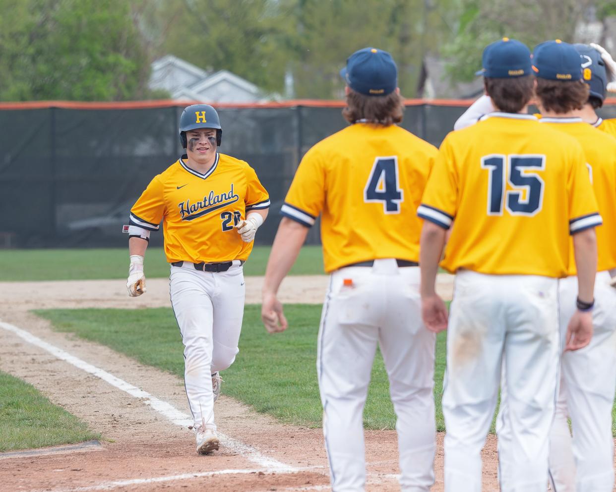 Hartland's Lucas Frack (20) heads toward teammates at home plate after hitting a two-run homer during a 6-4 victory over Brighton Monday, April 29, 2024.