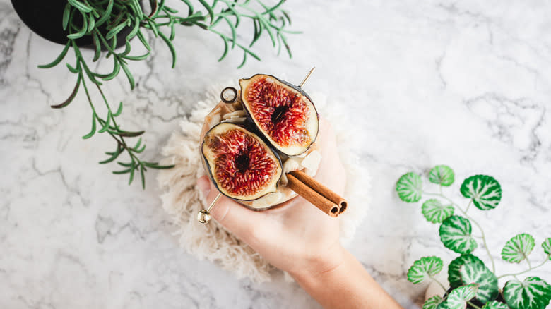 overhead view of smoothie garnished with figs on skewer, almonds and cinnamon