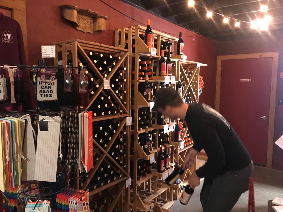 John Hackney, bartender and server at the Fenton Winery & Brewery, stocks bottles of craft wine in the gift shop area.