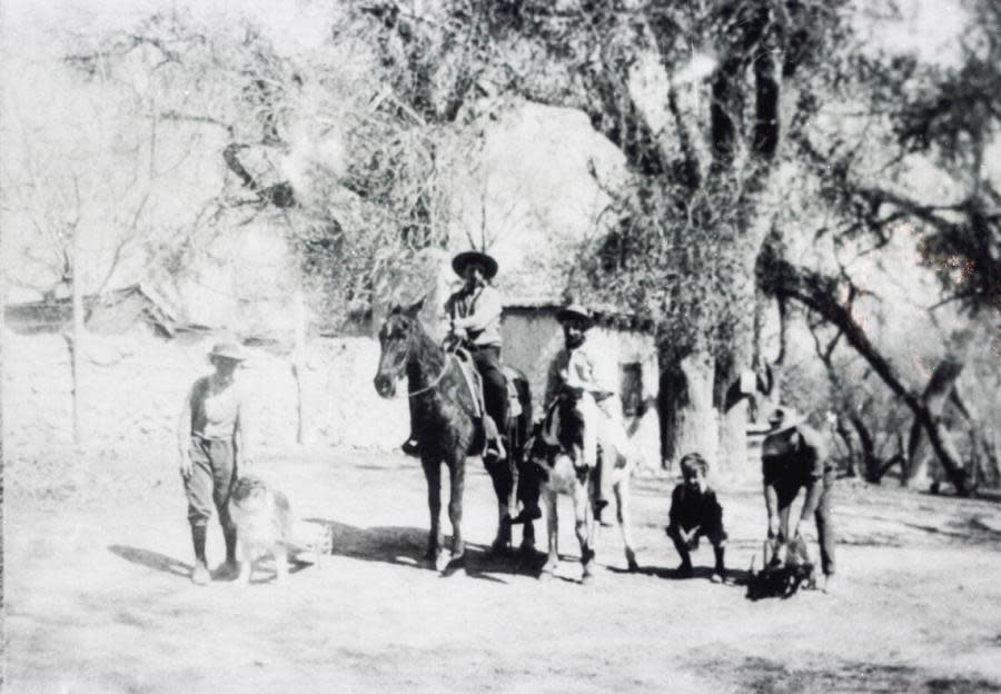 Men and a boy, horses, and dogs outside of buildings at the Las Vegas Mormon Fort, 1909. (UNLV Special Collections and Archives)