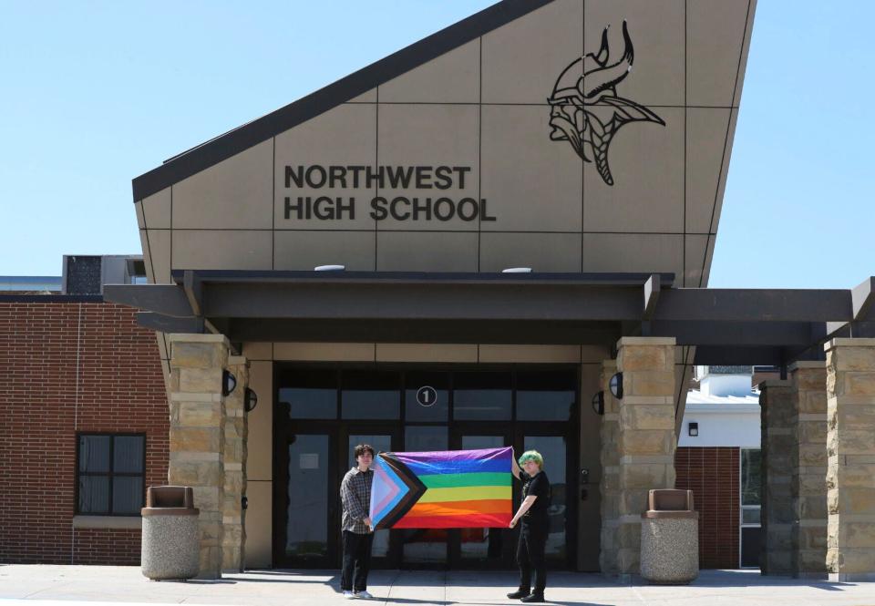 Former Viking Saga newspaper staff members Marcus Pennell, left, and Emma Smith, right, display a Pride flag outside Northwest High School in Grand Island, Neb., in July 2022. Administrators shuttered the school’s award-winning student newspaper, just days after its last edition included articles and editorials on LGBTQ issues.