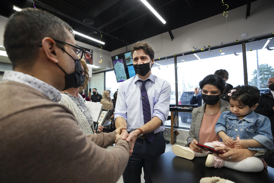 Canadian Prime Minister Justin Trudeau, center, shakes hands with Ahmad Najib Wahidi, left, and his daughter, 14-month-old Harir Wahidi, right, and mother Marghana Elyaskhil, center, as he meets with families who have resettled from Afghanistan at the Eastern Food Market in Hamilton, Ontario, on May 6, 2022. (Nathan Denette / The Canadian Press via AP file)