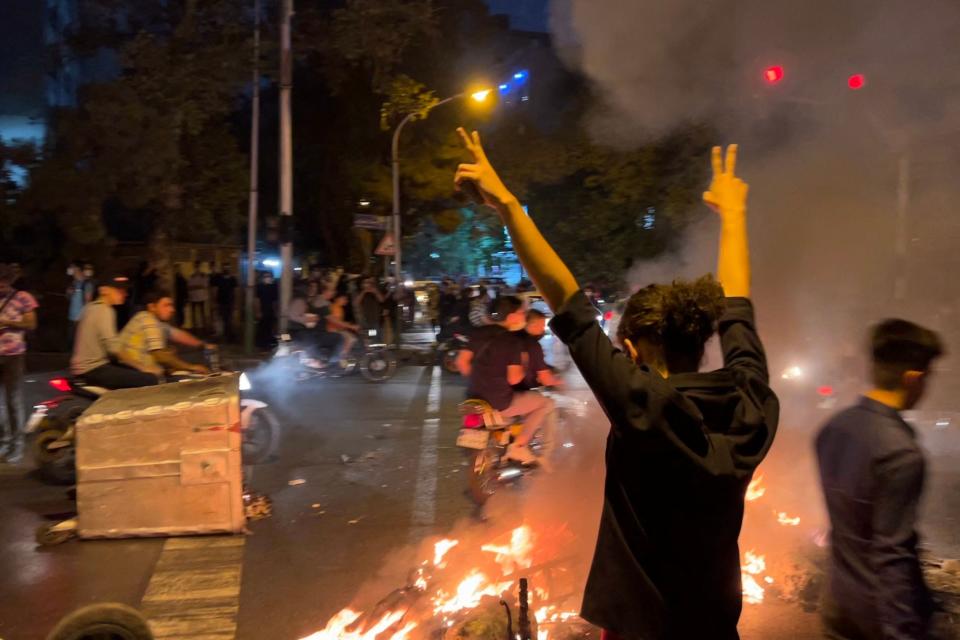 A demonstrator raises his arms and makes the victory sign during a protest for Mahsa Amini, a woman who died after being arrested by the Islamic republic's "morality police" in Tehran on Sept. 19, 2022.