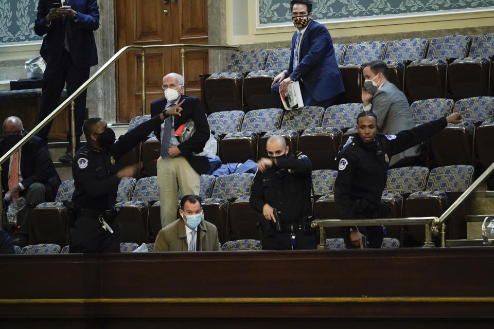 FILE - U.S. Capitol Police direct lawmakers to evacuate the House Chamber as rioters breach the Capitol in Washington, Wednesday, Jan. 6, 2021. (AP Photo/J. Scott Applewhite)