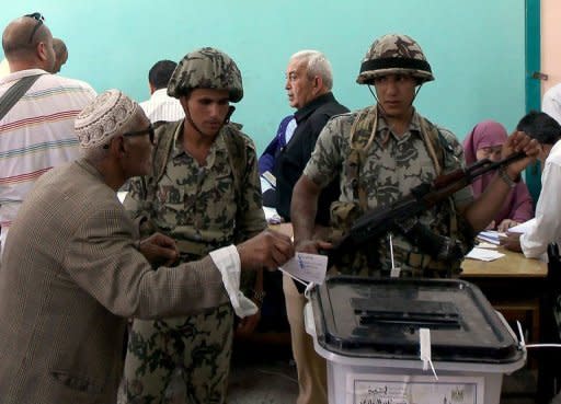 Egyptian soldiers stand guard next to a ballot box as an elderly man casts his vote in the second round of the historical presidential election at a polling station in the city of Zagazig. Egyptians voted on Saturday in a run-off presidential election pitting an Islamist against Hosni Mubarak's last premier as the military rulers entered a showdown with the Islamists by disbanding parliament