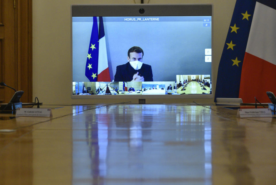 French President Emmanuel Macron is seen on a screen from his presidential residence in Versailles as he attends by video conference the weekly cabinet meeting at the Elysee Palace in Paris, Monday, Dec. 21, 2020. French President Emmanuel Macron held a cabinet meeting Monday via video, in which he indicated the French could enforce "systematic tests" as a condition for French nationals returning from Britain to France for the holidays. (Julien de Rosa/Pool Photo via AP)