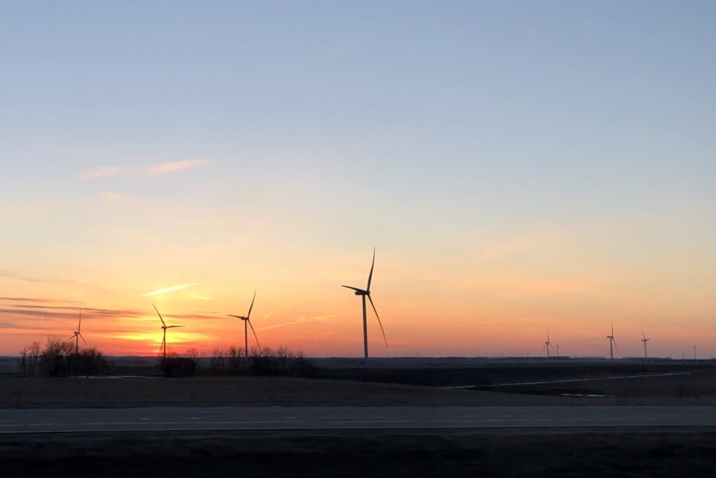 Wind turbines spin against the setting sun just north of Watertown along Interstate 29. (Makenzie Huber/South Dakota Searchlight)