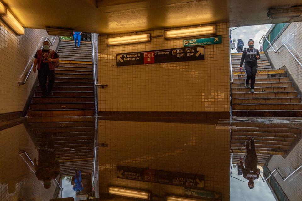 People walk down stairs into a flooded subway station.