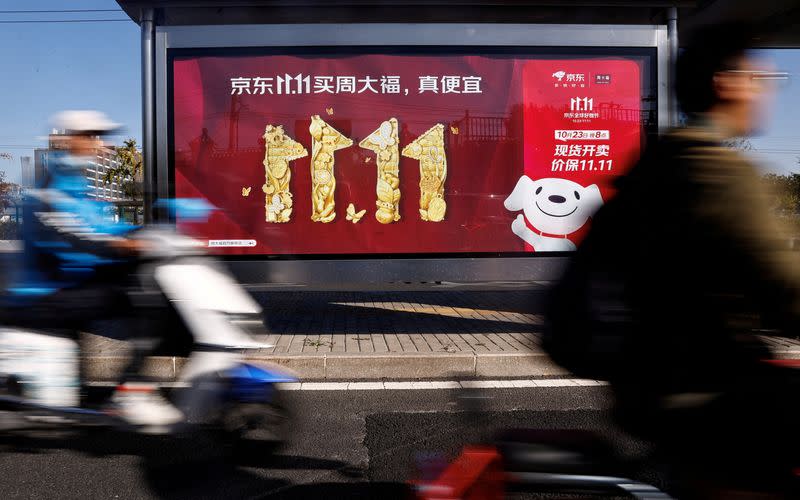 FILE PHOTO: People ride on a scooter past a JD.com's advertisement promoting Singles Day shopping festival, in Beijing