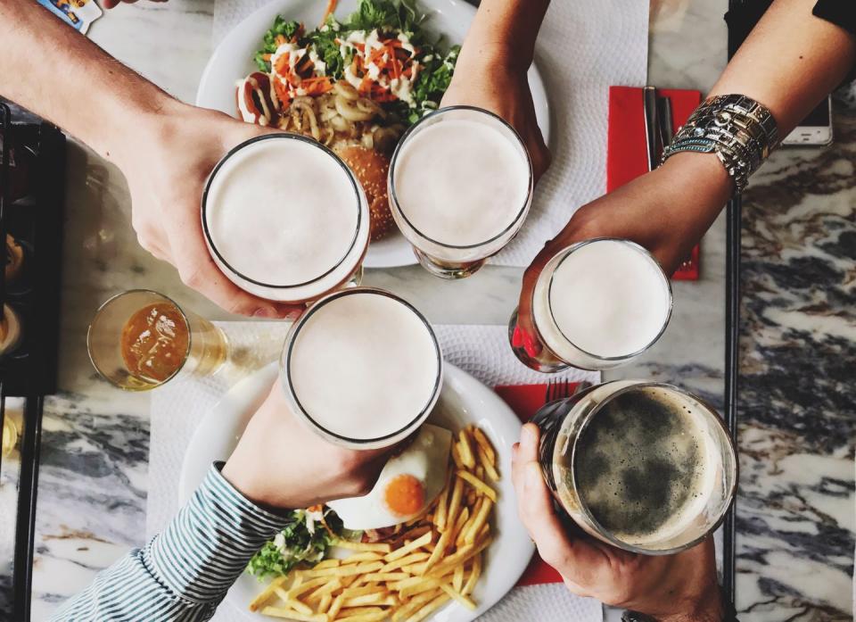 directly above shot of friends toasting alcohol glasses over table in restaurant