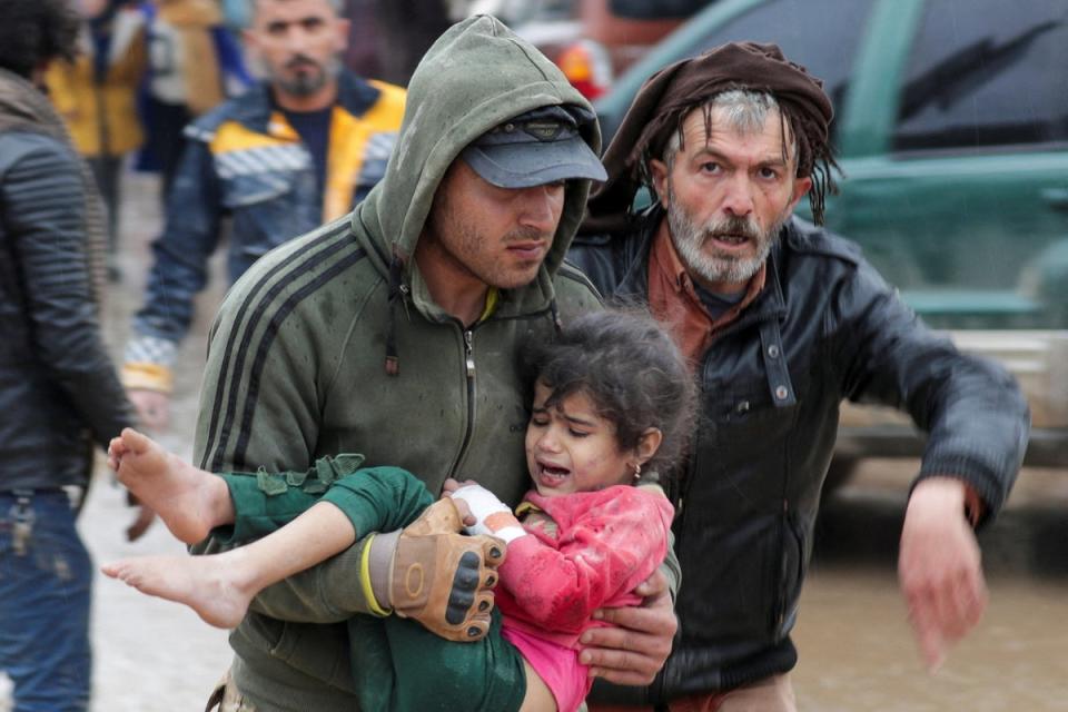 A man carrying a girl following the earthquake in the town of Jandaris, Syria (REUTERS)