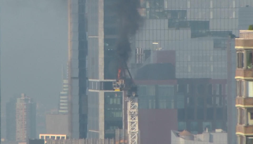 Emergency responders battle flames as a large construction crane caught fire in Manhattan on Wednesday, July 26, 2023 in New York. The crane caught fire and its arm hit a building as it crashed to the street below. (WABC via AP)