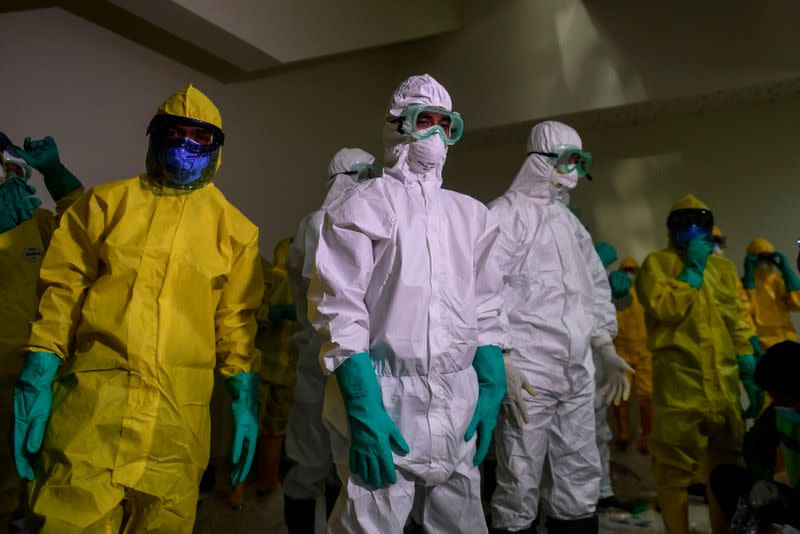 Officials wearing protective suits prepare to check Indonesians who were evacuated from the Diamond Princess cruise ship, before they are transported to Sebaru island for observation, at Kertajati International airport in Majalengka