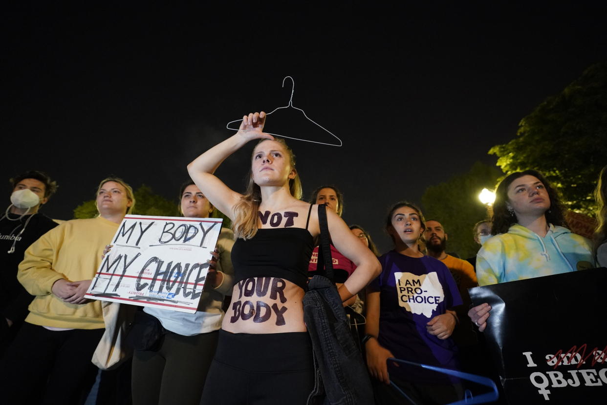 People holding signs and wearing body paint with the words: Not your body, and My body my choice.