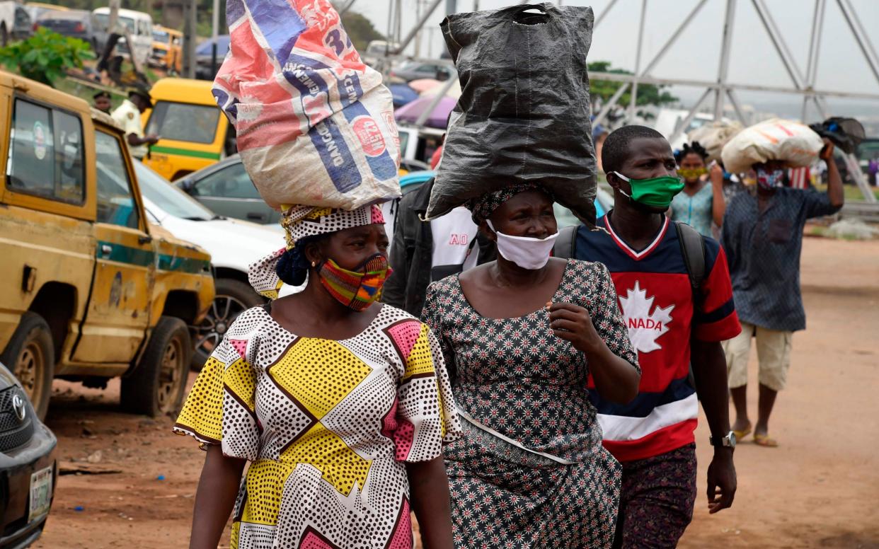People wears face masks in compliance with state directive to curb the spread of COVID-19 coronavirus at Ojodu-Berger in Lagos - AFP