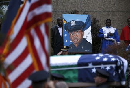 The casket of slain New York City Police (NYPD) officer Randolph Holder passes a painting of Holder, as it is carried from the Greater Allen A.M.E. Cathedral of New York following his funeral service in the Queens borough of New York City, October 28, 2015. REUTERS/Shannon Stapleton