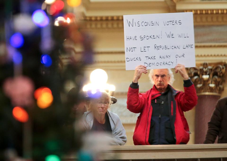 Bob Kinosian, from Wauwatosa, Wis., holds up a sign during the state Christmas Tree lighting ceremony in state Capitol Rotunda on Dec. 4, 2018, in Madison, Wis.