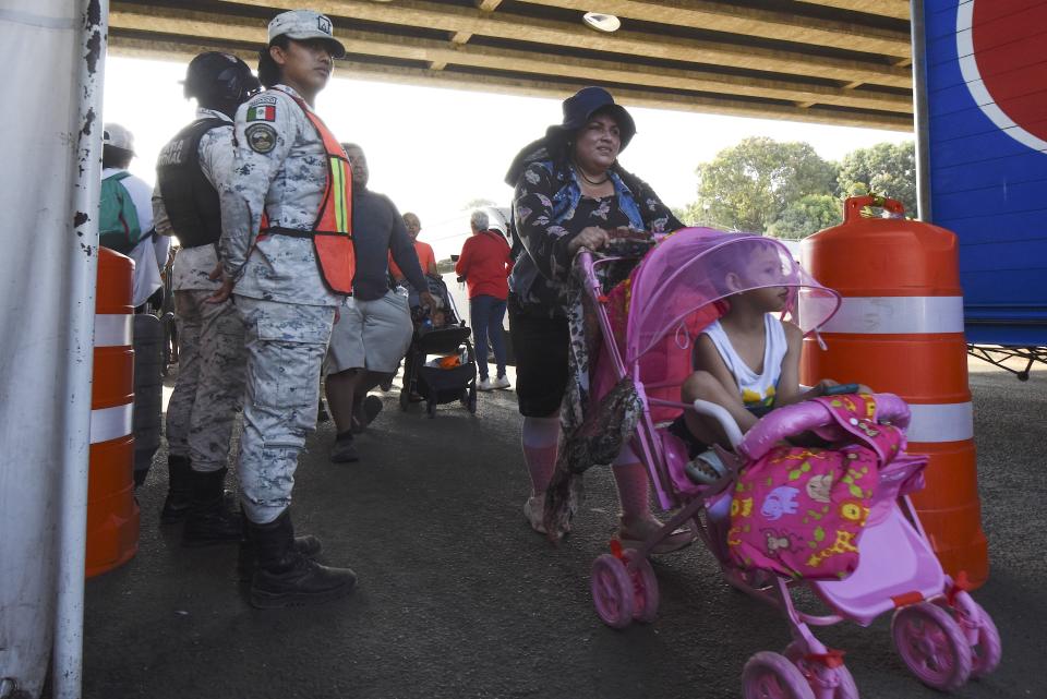 A migrant pushes a baby stroller past National Guards in Tapachula in Mexico's Chiapas state, Monday, March 25, 2024. Migrants stranded on the border with Guatemala departed on Monday for Mexico City in what they are calling "The Migrant Way of the Cross" during Holy Week to call for better migratory policies. (AP Photo/Edgar H. Clemente)