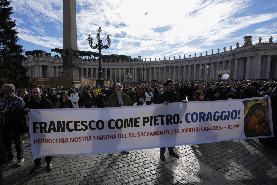 Faithful hold a banner with writing reading "Francis like Peter. Courage!" as a giant screen broadcasts Pope Francis during the Angelus noon prayer, from the chapel of the hotel at the Vatican grounds where he lives, Sunday, Nov. 26, 2023. Pope Francis says he has a lung inflammation but will go later this week to Dubai for the climate change conference. Francis skipped his weekly Sunday appearance at a window overlooking St. Peter's Square, a day after the Vatican said he was suffering from a mild flu. (AP Photo/Alessandra Tarantino)
