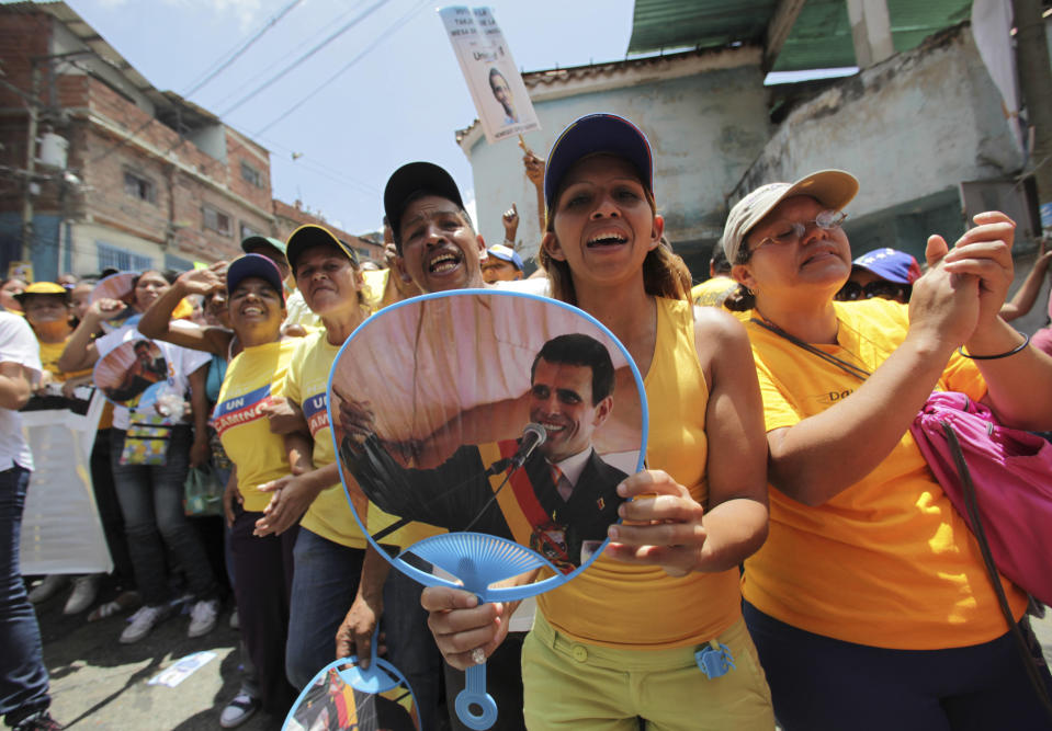 Supporters of opposition presidential candidate Henrique Capriles, one showing an image of him, cheer during a campaign rally in Caracas, Venezuela, Sunday, Sept. 16, 2012. Capriles is running against President Hugo Chavez in the country's Oct. 7 election. (AP Photo/Fernando Llano)