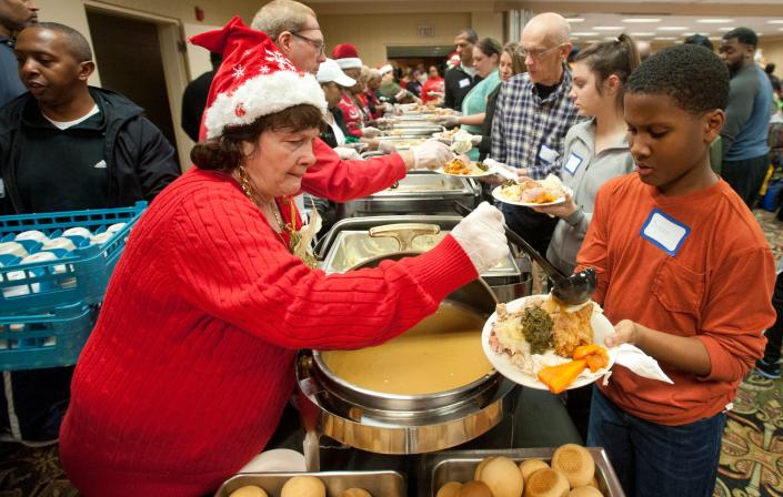 Volunteer Patty Calvert of Portland ladles some hot gravy over mashed potatoes on a plate held by volunteer Bryson Roberson of St. Andrews, who served guests. Calvert said she had been serving meals since 5 a.m. as the Wayside Christian Mission marked its 25th year of providing families a hot Christmas meal.