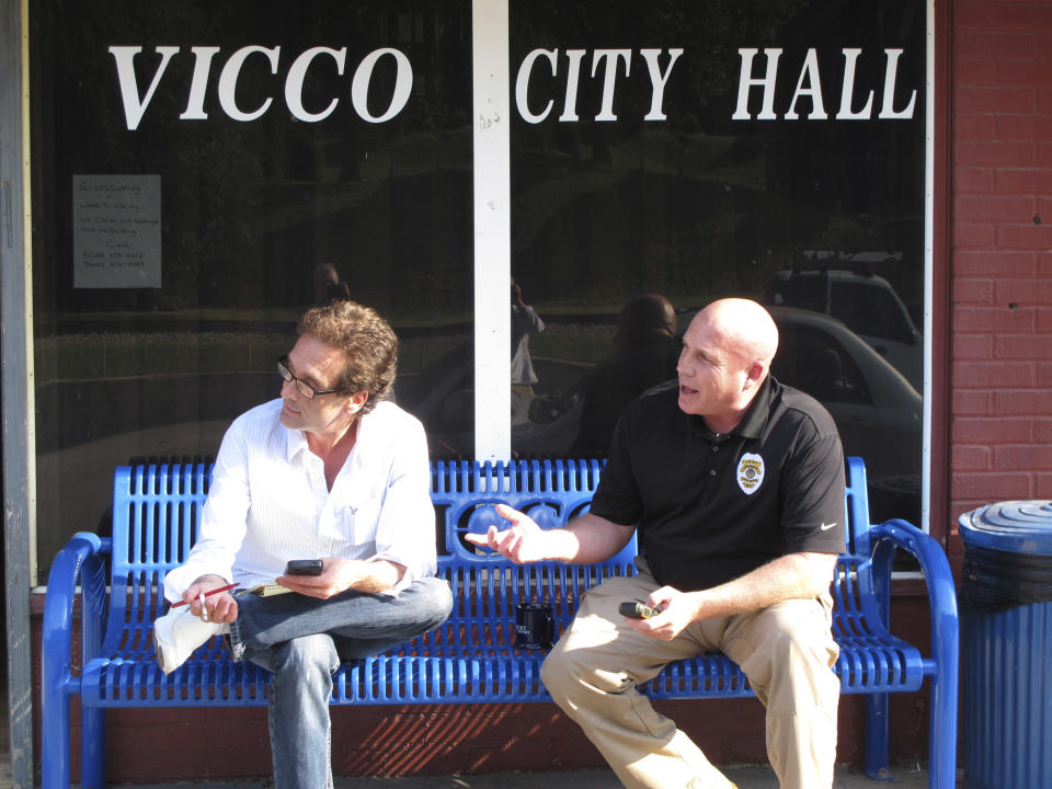 In this Monday, Sept. 16, 2013 photo, Vicco Mayor Johnny Cummings, left, and Police Chief Tony Vaughn sit in front of the city hall in the Appalachian town of Vicco, KY, Eight months after the tiny town took a stand against gay-based discrimination, it's basking in a flurry of attention and even an infusion of much-needed cash. All that hoopla has its openly gay mayor dreaming of reviving a place that had long seemed past its prime. (AP Photo/Bruce Schreiner)