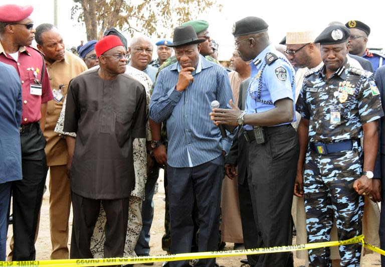 Nigerian President Goodluck Jonathan (C) and Senate President David Mark (C left) look at the spot a bomb attack in Abuja on April 14, 2014