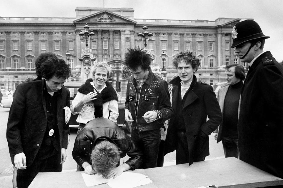 The Sex Pistols, signing a new recording contract with A&M Records outside Buckingham Palace in London with their manager Malcolm McLaren (1977) (PA)