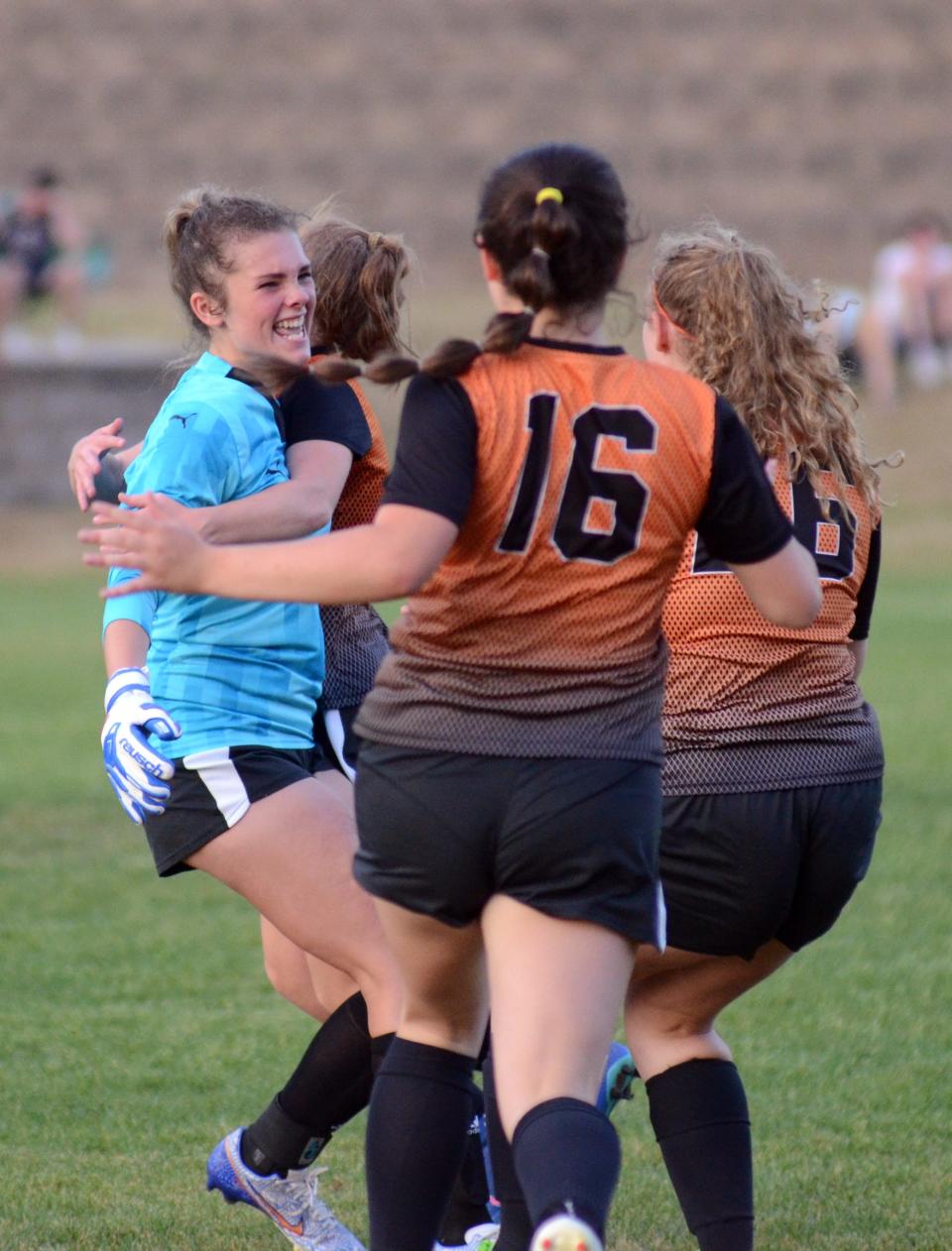 Harbor Springs players rush off the sidelines to senior keeper Hailey Fisher (left) following the shootout.