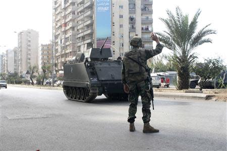 A Lebanese army soldier gestures to an armoured vehicle in Tripoli, northern Lebanon, November 30, 2013. REUTERS/Stringer