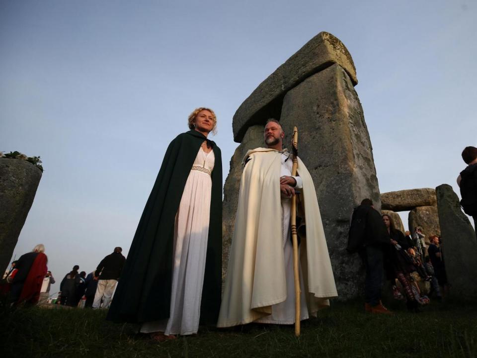 Those clothed in druid costume watch the sun rise on the Stonehenge monument (REUTERS)