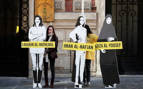 Protestors stand outside the Saudi embassy in Paris holding cardboard cutouts of imprisoned women's rights activists - Credit: REUTERS/Benoit Tessier