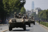 Soldiers patrol in armored vehicles as a state of emergency remains in effect in Santiago, Chile, Sunday, Oct. 20, 2019. Protests in the country have spilled over into a new day, even after President Sebastian Pinera cancelled the subway fare hike that prompted massive and violent demonstrations. (AP Photo/Luis Hidalgo)