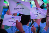 FILE - Participants wave flags with the logos of 2022 Beijing Winter Olympics and Paralympics before a launch ceremony to reveal the motto for the Winter Olympics and Paralympics in Beijing on Sept. 17, 2021. The Beijing Winter Olympics open in just under two months and are now the target to a diplomatic boycott by the United States with others likely to follow. (AP Photo/Mark Schiefelbein, File)