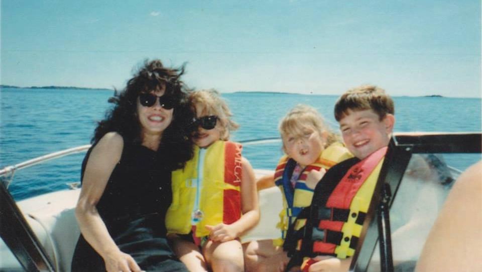 A mom and her three kids on a boat on a sunny day