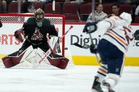 Arizona Coyotes goaltender Karel Vejmelka, left, gets set to make a save on a shot from Edmonton Oilers defenseman Tyson Barrie, right, during the first period of an NHL hockey game Thursday, Oct. 21, 2021, in Glendale, Ariz. (AP Photo/Ross D. Franklin)