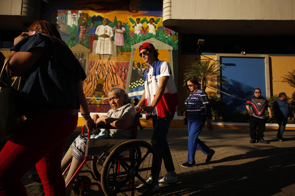 An election volunteer helps a woman in a wheelchair reach her voting table during the presidential election in San Salvador, El Salvador, Sunday, Feb. 3, 2019. Salvadorans are choosing from among a handful of presidential candidates all promising to end corruption, stamp out gang violence and create more jobs in the Central American nation. (AP Photo/Salvador Melendez)